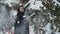 Handsome lady shakes the snowy fir-tree branches in the park