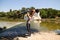 Handsome latin man and beautiful latin woman dancing bachata by the river. The man holds the woman horizontally above his head.