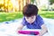 Handsome little boy is addicted social media or online game by always playing on tablet all day and every time. Lovely kid is atte