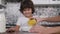 Handsome little boy sitting at the table and waiting while his mother filling the bowl with corn flakes