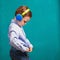 Handsome little stylish boy in bright headphones standing and li