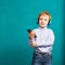 Handsome little stylish boy in bright headphones standing and li