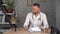 A handsome male doctor sits at a table in a white coat to communicate by video communication through his smartphone