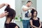 Handsome male hairdresser is making hair styling for his client at the beauty salon