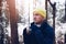 Handsome male hiker in yellow cap is eating a hamburger and resting on the trail.