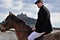 Handsome male rider on horse with flatcap in front of old castle