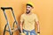 Handsome man with beard by construction stairs wearing hardhat angry and mad screaming frustrated and furious, shouting with anger