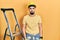 Handsome man with beard by construction stairs wearing hardhat depressed and worry for distress, crying angry and afraid