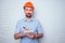 Handsome man with a beard and a helmet hardhat on a background of a white brick wall builder holding notebook