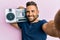 Handsome man with beard holding boombox, listening to music smiling with a happy and cool smile on face