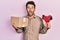 Handsome man with beard holding packing tape holding cardboard afraid and shocked with surprise and amazed expression, fear and