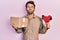 Handsome man with beard holding packing tape holding cardboard looking at the camera blowing a kiss being lovely and sexy