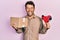 Handsome man with beard holding packing tape holding cardboard smiling and laughing hard out loud because funny crazy joke