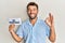 Handsome man with beard holding paper with 3d printing text doing ok sign with fingers, smiling friendly gesturing excellent