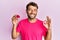 Handsome man with beard holding pink geode precious gemstone doing ok sign with fingers, smiling friendly gesturing excellent