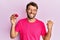 Handsome man with beard holding pink geode precious gemstone screaming proud, celebrating victory and success very excited with