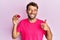 Handsome man with beard holding pink geode precious gemstone smiling happy and positive, thumb up doing excellent and approval