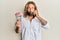 Handsome man with beard and long hair talking on the phone holding 100 new zealand dollars making fish face with mouth and