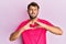 Handsome man with beard making heart symbol with hands shape puffing cheeks with funny face