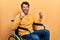 Handsome man with beard sitting on wheelchair angry and mad raising fists frustrated and furious while shouting with anger