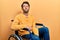 Handsome man with beard sitting on wheelchair looking at the camera blowing a kiss on air being lovely and sexy