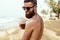 Handsome Man with beard, In Sunglasses Sunbathing With Sunscreen Lotion Body In Summer. Male Fitness Model Tanning Using Solar Blo