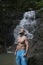 Handsome man with beard wearing blue shorts standing and looking up near waterfall