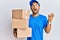 Handsome man with beard wearing courier uniform holding delivery packages crazy and mad shouting and yelling with aggressive