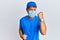 Handsome man with beard wearing courier uniform and medical mask celebrating surprised and amazed for success with arms raised and