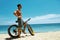 Handsome Man With Bike Sun Tanning On Beach. Summer Vacation.