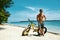 Handsome Man With Bike Sun Tanning On Beach. Summer Vacation.