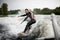 Handsome man in black swimsuit rides through the waves on water board