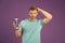 Handsome man with body isolated on purple background. Model with healthy hair holding shampoo bottle, body care and