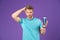 Handsome man with body on purple background. Model with healthy hair holding shampoo bottle, body care and