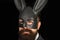 Handsome man in carnival mask ballroom rabbit with long ears sensual on a black background. Serious man with beard in
