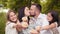 Handsome man and charming woman kissing while their two cute daughters holding cupcakes in hands smiling on camera