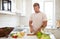 Handsome man cooking at home preparing salad in kitchen