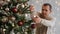 Handsome man decorating christmas tree with colorful baubles