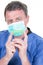 Handsome man doctor chemist hand in protective gloves blue mask hold test green coronavirus tube