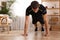 Handsome man doing high plank exercise on floor at home