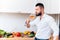 Handsome man drinking a glass of rose wine during dinner preparation. Modern cook sipping from wine while cooking salad