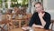 Handsome man drinking watermelon juice in stylish cafe, looks at camera, smiles