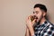 Handsome man eating tasty burger on color background