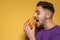 Handsome man eating tasty burger on color background