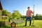 Handsome man farmer pushing wheelbarrow with freshly picked organic vegetables. Healthy vegetarian food. Harvesting. Veggies for