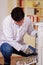 Handsome man fixing a photocopier during maintenance using a screwdriver wearing work gloves