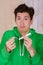 Handsome man with a funny face holding a menstruation cotton tampon, wearing a green hoodie in a blurred background