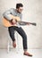 Handsome man holding an acoustic guitar against grunge wall