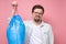 Handsome man holding blue garbage bag isolated on pink background