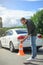 handsome man holding car insurance and putting safety cones